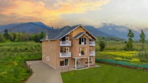 a house in a field with mountains in the background at Royal Cliff Resort Pahalgam in Pahalgām