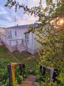 a small white house with a porch and a wooden stairs at Birchington Vale - Delta Lodge in Kent