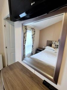 a mirror in a bedroom with a bed in it at Birchington Vale - Delta Lodge in Kent