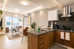 a kitchen with a sink and a living room at Comfy City Center 1BR Condo in Los Prados