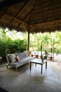 a couch and a coffee table under a straw umbrella at Villa Wayra in Santa Teresa Beach