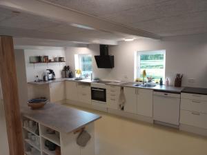 a large kitchen with white cabinets and a table at Sønderhedens B&B in Vrå +5 photos