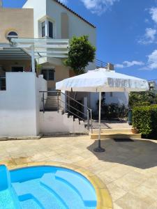 a white umbrella and a swimming pool in front of a house at Villa Flash in Eantio