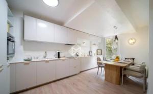 a kitchen with white cabinets and a wooden table at Maison Azur -Luxury Townhouse Garden -Parking -Croix des Gardes in Cannes