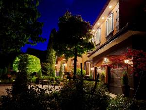 a house with a lit up yard at night at Villa Bellissimo FranTállia - Beautéssera & Galleríseum in Kelowna