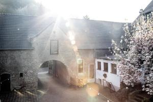 an archway in a brick building with the sun shining at Hostel Burg Hausen in Heimbach
