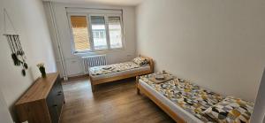 a room with two beds and a table and a window at Ira's Square 2 Bedroom Free Parking in Skopje