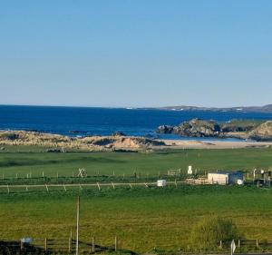 a green field with the ocean in the background at Ocean Heights House in Dunfanaghy