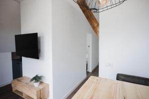 a living room with a table and a tv on a wall at vredehof appartement in Sint Maartensbrug
