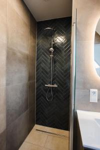 a shower in a bathroom with a black tile wall at vredehof appartement in Sint Maartensbrug +31 photos