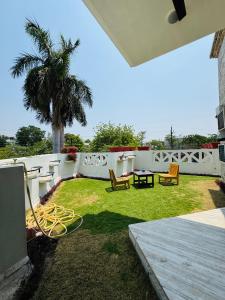 a yard with chairs and a table and a palm tree at The Regalis Villa in Lucknow