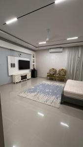 a living room with a tv and a bed and chairs at Ghala Farm in Adh Dhayd