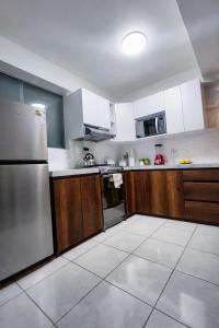 a kitchen with wooden cabinets and a stainless steel refrigerator at Amatista Apartment in Cusco