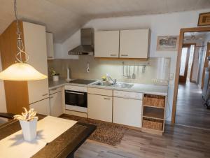 a kitchen with white cabinets and a sink and a table at Dreiflüsse Appartement - Traumgarten mit Grill und Pavillon, WLAN, Küche und Parkplatz in Salzweg