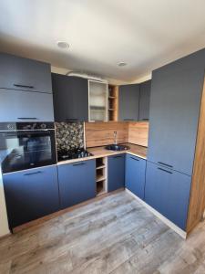 a kitchen with blue cabinets and wooden floors at MV Apartament in Druskininkai