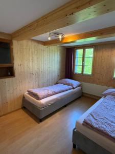 two beds in a room with wooden walls and wooden floors at Ferienwohnung Bürgenblick in Kehrsiten