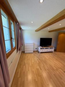 a living room with a flat screen tv and a wooden floor at Ferienwohnung Bürgenblick in Kehrsiten