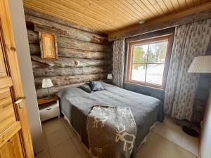 a bedroom with a bed in a log cabin at Usva Cabins Ylläs - Sapara J 38 in Äkäslompolo