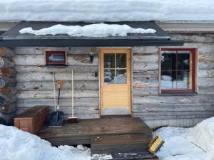 a wooden cabin with a door in the snow at Usva Cabins Ylläs - Sapara J 38 in Äkäslompolo