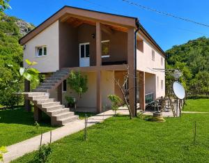 a house with stairs and a grass yard at Djekljak House in Virpazar