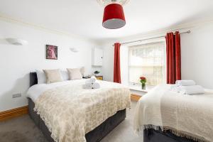 two beds in a bedroom with red curtains at Central Basement Flat-Parking-By FabAccommodation in Bristol