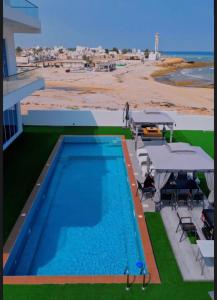 a swimming pool with picnic tables and a view of the beach at شاليهات الجوهرة in Fins