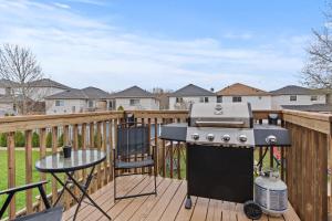 a grill on a deck with a table and a chair at 3 Bedroom suite Upper Level of House 8 guests in Barrie