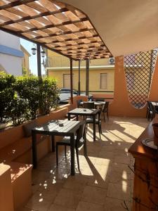 a patio with tables and chairs under a pergola at B&B De Janas in La Caletta
