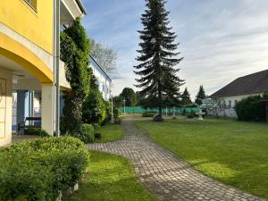 a brick walkway next to a house with a tree at Thermal Oazis Apartman in Mosonmagyaróvár