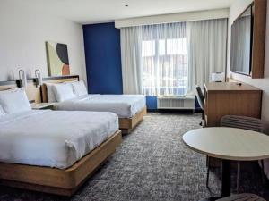 a hotel room with two beds and a table at Spark by Hilton Montreal Brossard in Brossard