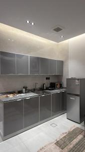 a kitchen with gray cabinets and a refrigerator at Spacious Two-Bedroom Apartment with a Large Living Room, comfortable and well organized, perfect for a relaxing stay in Jeddah