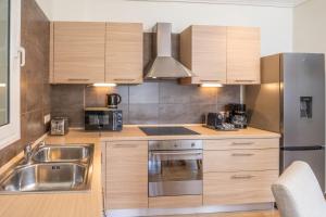 a kitchen with wooden cabinets and a stainless steel refrigerator at Aura Seaside Apartment in Karavomylos