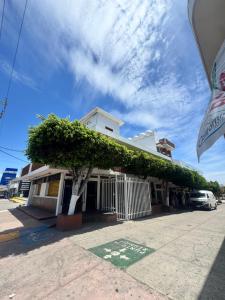 a white building with a tree in front of it at Hotel California in Mazatlán
