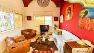 a living room with red walls and leather furniture at Dar Kmaar in Hammamet