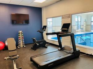 a gym with a treadmill and a swimming pool at Spark by Hilton Montreal Brossard in Brossard +2 photos