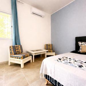 a bedroom with a bed and two chairs and a table at Dar Kmaar in Hammamet