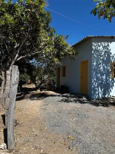 a white house with a yellow door and a tree at Cantinho da Naná in Cavalcante