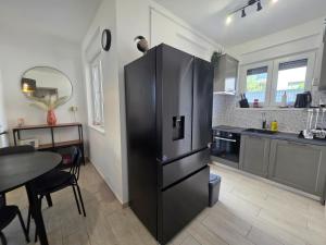 a large black refrigerator in a kitchen with a table at Summer house Le Vito in Tribunj