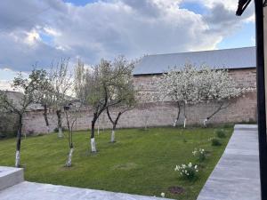 a group of trees in a yard next to a brick wall at White House Byurakan in Byurakan