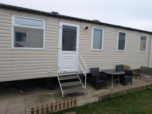 a house with a door and a table and chairs at Jaynes Holiday Caravan Marton Mere in Blackpool
