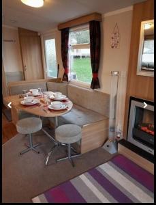 a living room with a table and a fireplace at Jaynes Holiday Caravan Marton Mere in Blackpool +4 photos