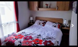 a bedroom with a bed with a floral bedspread at Jaynes Holiday Caravan Marton Mere in Blackpool