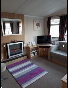 a living room with a couch and a flat screen tv at Jaynes Holiday Caravan Marton Mere in Blackpool