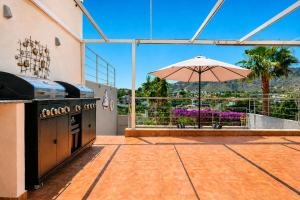 an outdoor kitchen with an umbrella on a patio at Exquisite Costa Blanca Escape Townhouses in El Campello +16 photos