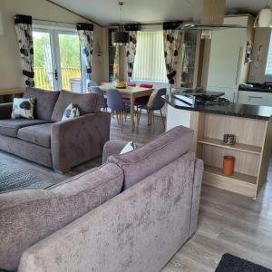 a living room with a couch and a table and a kitchen at Trevella Lakeview Lodge in Newquay