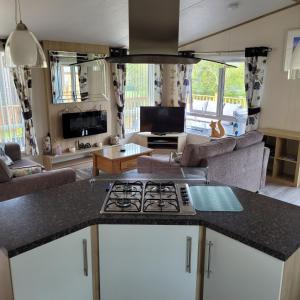 a kitchen and living room with a stove top at Trevella Lakeview Lodge in Newquay