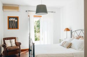 a bedroom with a bed and a chair and a window at Just Like Home - Casa do Sobreiro Velho em Cerveira in Vila Nova de Cerveira