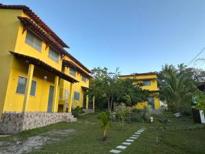 a yellow house with a yard in front of it at Ilha de Boipeba kitnets para temporada - Morada dos Pássaros Boipeba in Ilha de Boipeba