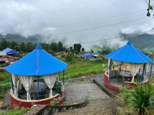 two gazebos with blue roofs on a hill at Chautari Hotel & Restaurant in Astam
