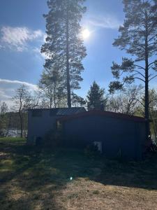 a small blue building in a field with trees at Domek nad jeziorem Gowidlińskim in Podiazy